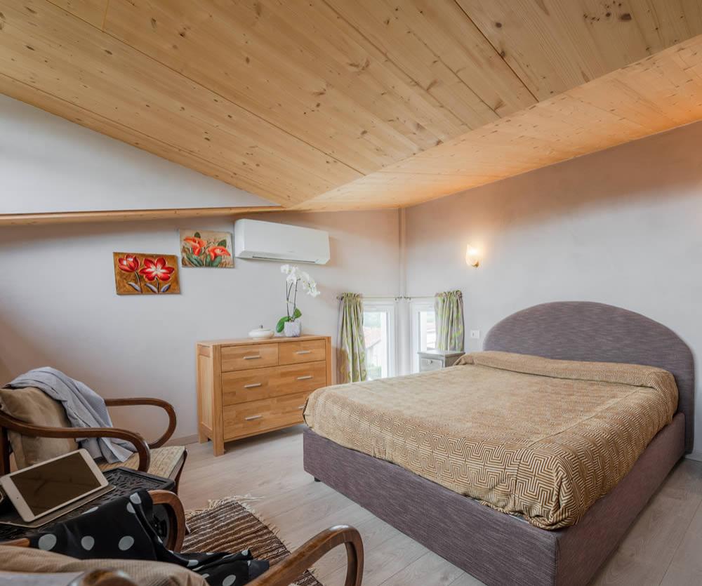 Camera accogliente con letto matrimoniale, soffitto in legno e decorazioni floreali.