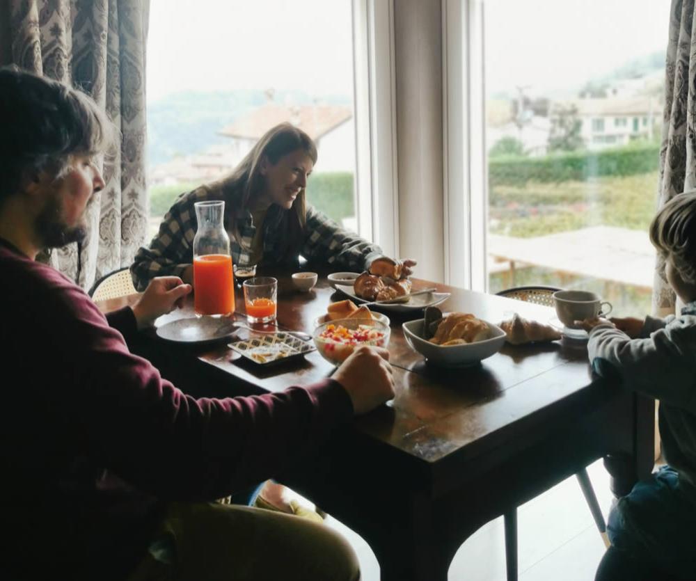 Famiglia a colazione con succo d'arancia, croissant e vista panoramica.